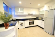 The spacious kitchen is outfitted with a stove, oven, large refrigerator, microwave oven and a washing machine.  