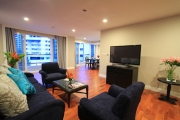 The large open living room with sofa, armchairs and a large flat screen tv.